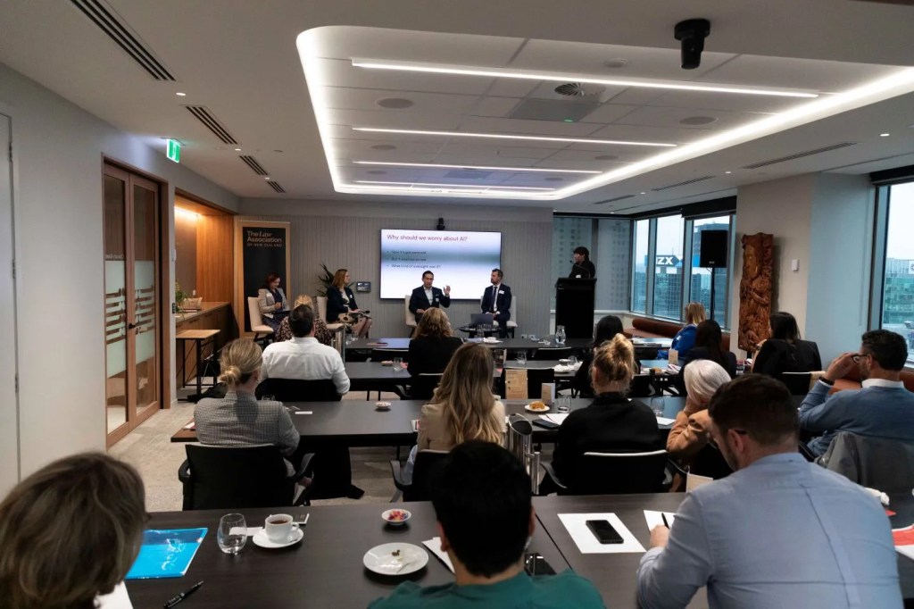A full conference hall with speakers seated on a raised stage